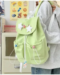 Detail view of a cute light green backpack with plush star charms and white drawstrings.