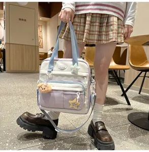 Sac à bandoulière étudiant en toile multi-poches avec de jolis charms, spacieux et pratique.