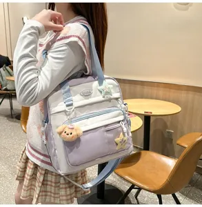 Vue détaillée du sac à dos bandoulière pastel violet et blanc avec charm d'ours en peluche.