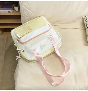 Vue détaillée du sac à dos scolaire en toile jaune et blanche avec bretelles roses et poches.
