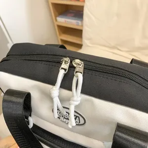 Vue détaillée du sac à dos scolaire noir et blanc avec fermetures éclair doubles.
