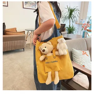 Detalle del bolso cruzado de lona amarilla con adorable oso de peluche y bonito colgante.