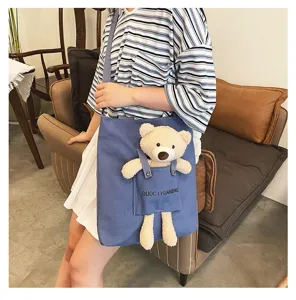 Vista detallada del bolso bandolera de lona informal con bolsillo de oso de peluche.