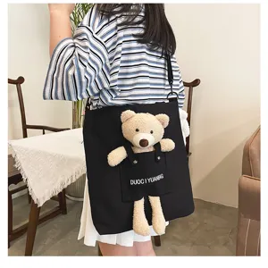 Detalle de primer plano del bonito oso de peluche en el bolso bandolera de lona negra.