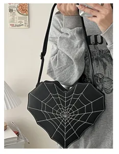Detail shot of black heart-shaped crossbody bag with white spiderweb stitching design.