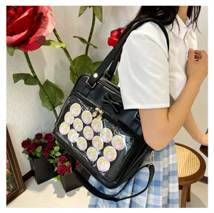 Black ita bag with transparent front pocket and cute bow, decorated with anime character badges.
