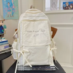 Gedetailleerd overzicht van de schattige beige canvas rugzak met mooie borduurwerk en strikken.