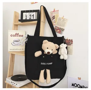 Vista detallada del bolso de lona negro con lindo oso de peluche y bonito colgante de muñeca.