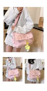 Detail view of pink floral canvas messenger bag with wide strap and cute flower pendant charm.