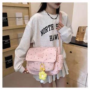 Detailed view of pink floral canvas messenger bag with cute yellow flower pendant and flap.