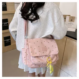 Detailed view of a pink floral canvas messenger bag worn on shoulder, student daily bag.