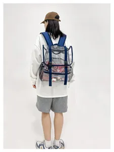 Detailed view of the clear PVC backpack with blue straps, worn by model in studio.