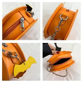 Detail view of Halloween pumpkin shaped novelty shoulder bag with chain strap and bat charm.