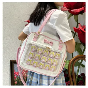 Cute pink and white ita bag featuring clear window and anime character badges for daily uniform wear.