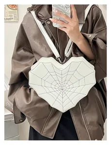 Detail shot of the white heart spiderweb crossbody bag worn with a cool leather jacket.