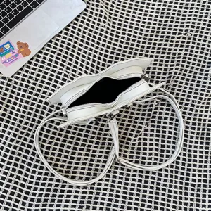 Details of the unique heart bat shaped white crossbody bag with multi-functional straps.