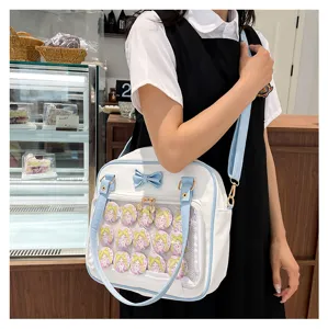 Cute blue and white ita bag with clear window, decorative bow, and anime character pins for daily fashion.