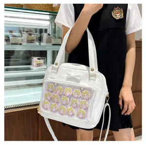 Detailed view of a white ita bag with transparent window, cute bow, and anime character badges.