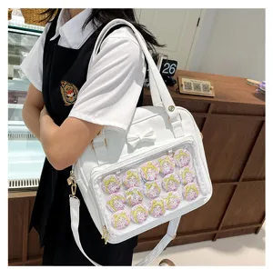 White ita bag detail with clear pocket and bow, featuring anime badges and strap.