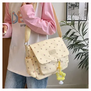 Detail view of casual floral canvas messenger bag featuring cute charm and strap.
