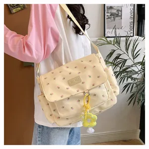 Detailed view of the cute yellow floral canvas messenger bag with a stylish pendant for students.