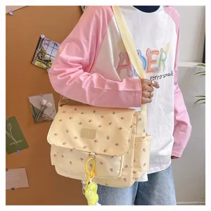 Casual floral canvas messenger bag detail with cute floral pattern, front pocket and charm.