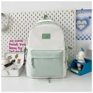 Detail shot of white and light green canvas backpack with front pocket and rubber patch.