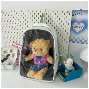Detail shot of clear front ita backpack in light green, featuring plush doll display window.