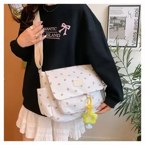 Canvas messenger bag for students, large capacity floral shoulder bag with cute flower pendant.