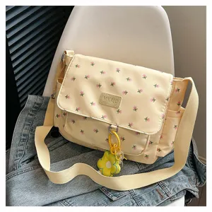 Detail view of the cute floral canvas messenger bag with brand badge and yellow flower charm.