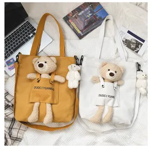 Detalle de bolso cruzado de lona con bonito osito de peluche, diseño flat lay estético y chic.