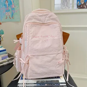 Gedetailleerd overzicht van de roze studentenrugzak met zoete borduurstiksels en strikjes.