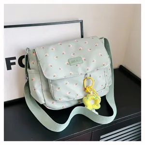 Detailed view of the sage green floral canvas messenger bag with cute flower charm and strap.