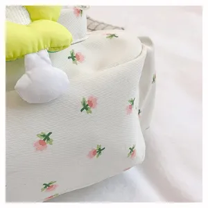 Close-up detail of Japanese style floral canvas messenger bag with cute flower plush decor.
