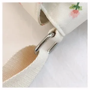 Detailed view of canvas crossbody bag strap with metal buckle and floral pattern.