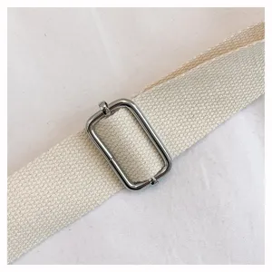 Detailed view of the adjustable canvas shoulder strap and shiny metal buckle for bags.