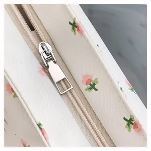 Close up view of floral canvas fabric pouch showing detailed zipper and pink flower print.