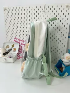 Side detail view of the light green transparent doll backpack with clear front pocket display.