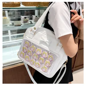 White PU leather ita bag with cute bow and clear window displaying anime character badges for daily use.