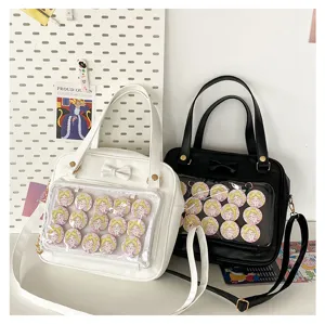 Detail view of cute ita bag with transparent front pocket, bow decoration and anime badges.