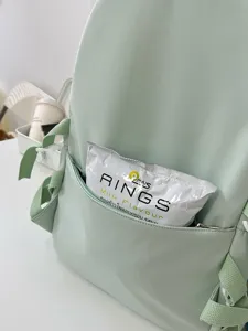 Japanese style light green backpack detailed close-up showing front zipper pocket and strap design.
