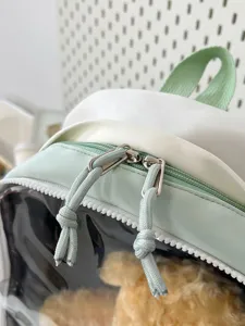 Close-up detail of green white backpack transparent pocket dual zippers fabric texture style.