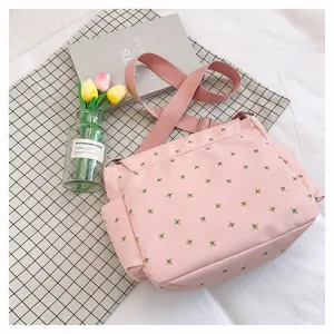 Close-up detail of the pink floral canvas messenger bag showing the delicate fabric and adjustable strap.
