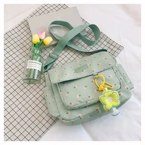 Green floral messenger bag detail shot, showing large capacity, cute pendant and fabric.