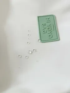 Waterproof backpack fabric detail showing water repellent surface and green brand patch