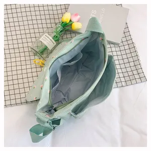 Detailed view of the mint green floral canvas messenger bag showing internal pockets.