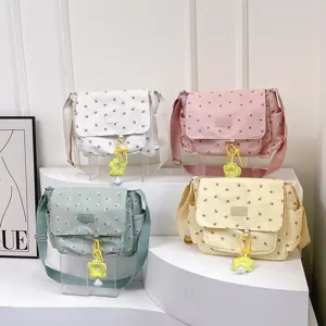 Detailed view of cute floral canvas messenger bags in multiple colors with lovely charms.
