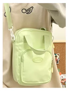 Detailed close-up view of the light green crossbody bag front pocket and carry handle.