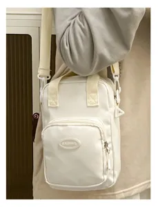Close-up detail of white canvas crossbody small bag with front zipper pocket and strap.