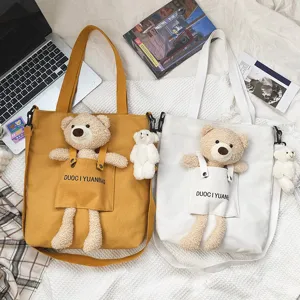 Vista detallada de bolso de lona con osito de peluche y diseño de bolsillo, bonita disposición.
